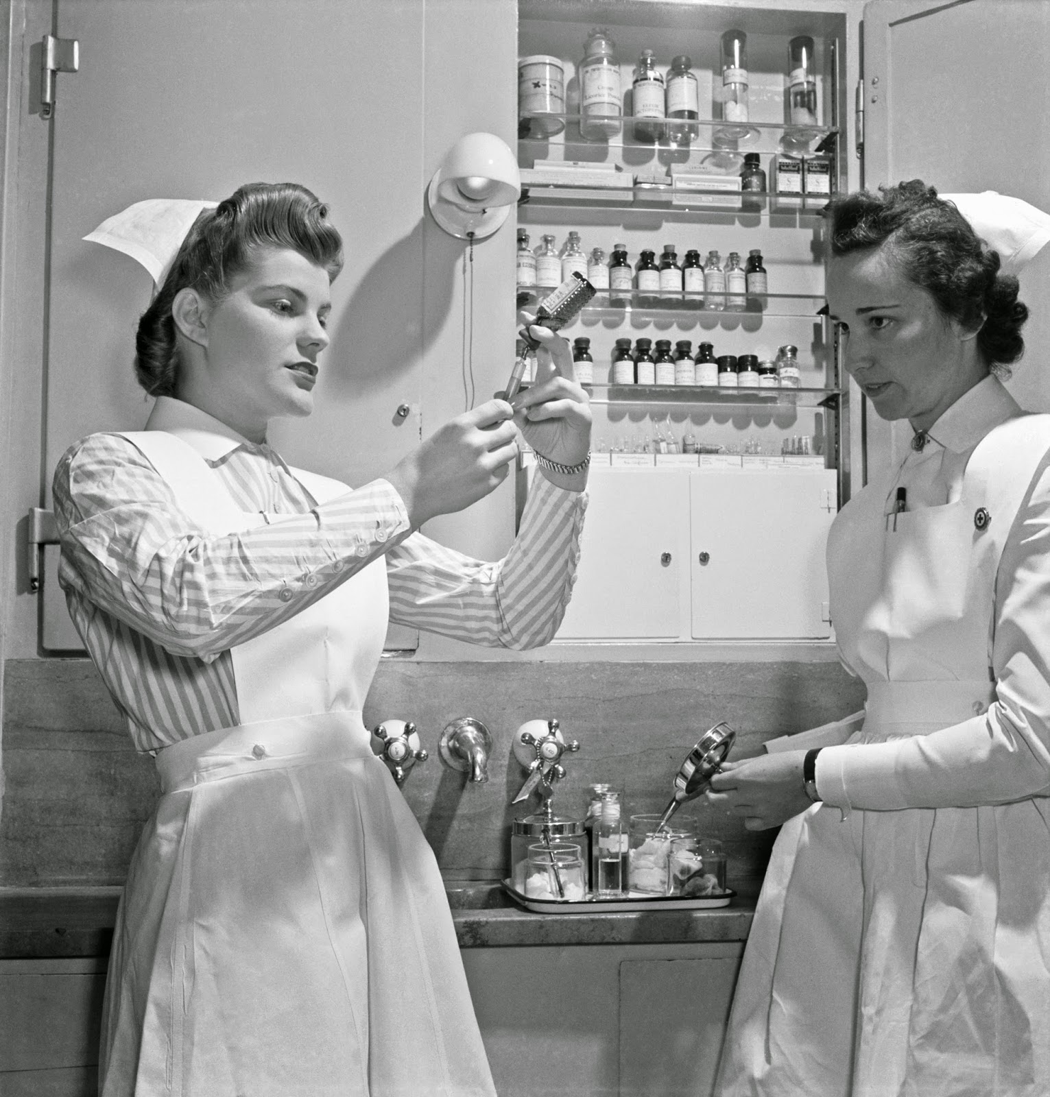Nurse training. A graduate nurse (right) watches student Susan Petty prepare a hypodermic for a patient. Strict adherence to doctors' orders is something every probationer must learn, 19